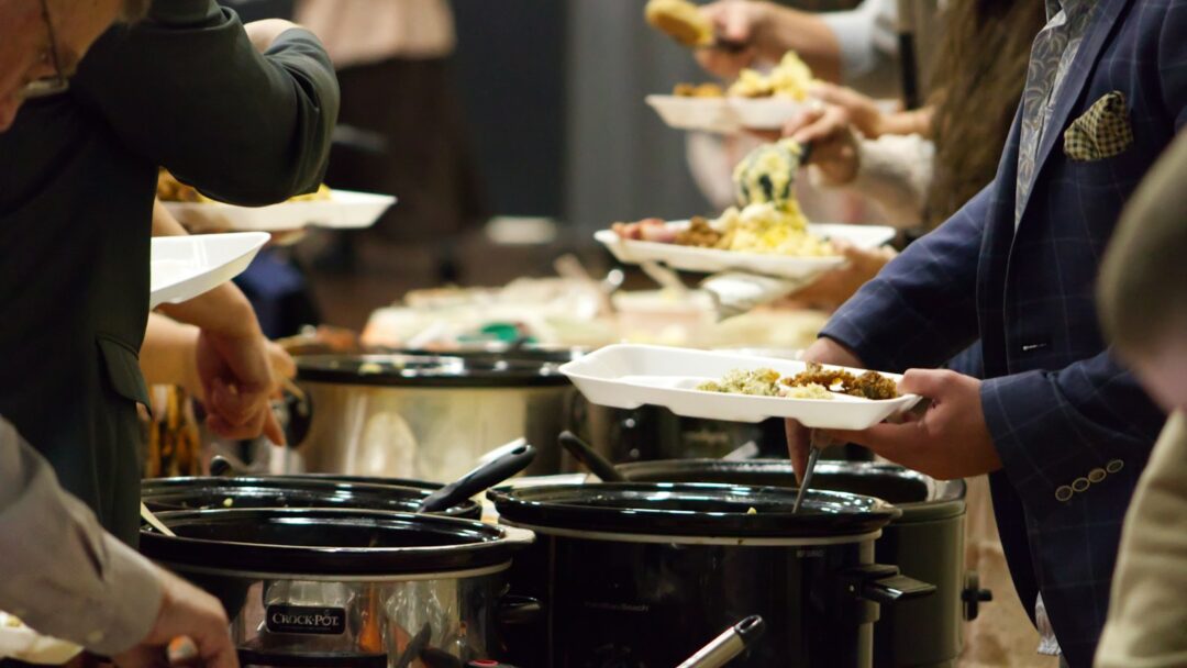 A group of people standing around a buffet line